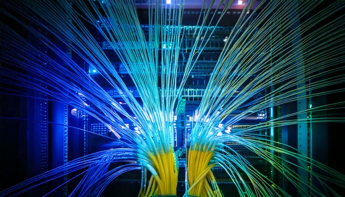 An image of a supercomputer server with photonics cables. The photonics cables with laser light.